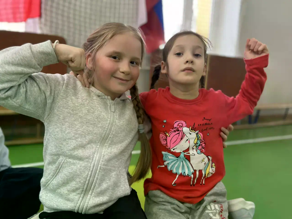 две девочки показывают свою силу в шуточной форме руками показывая мышцы 