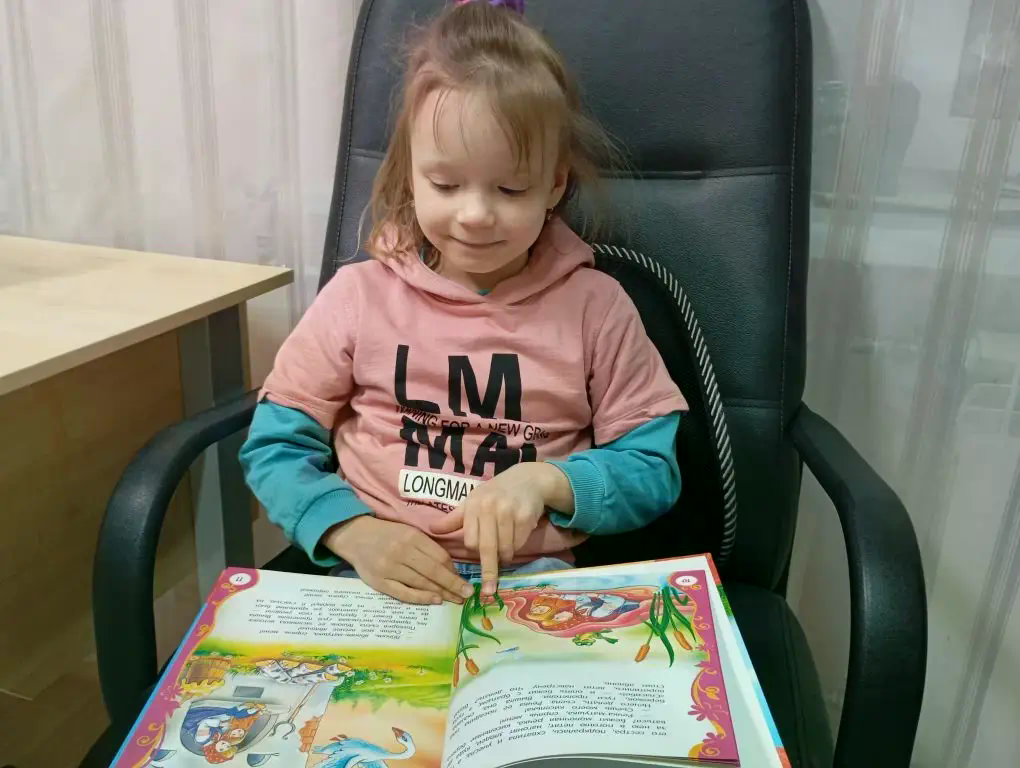 деовчка смотрит картинки из книг сказок.png