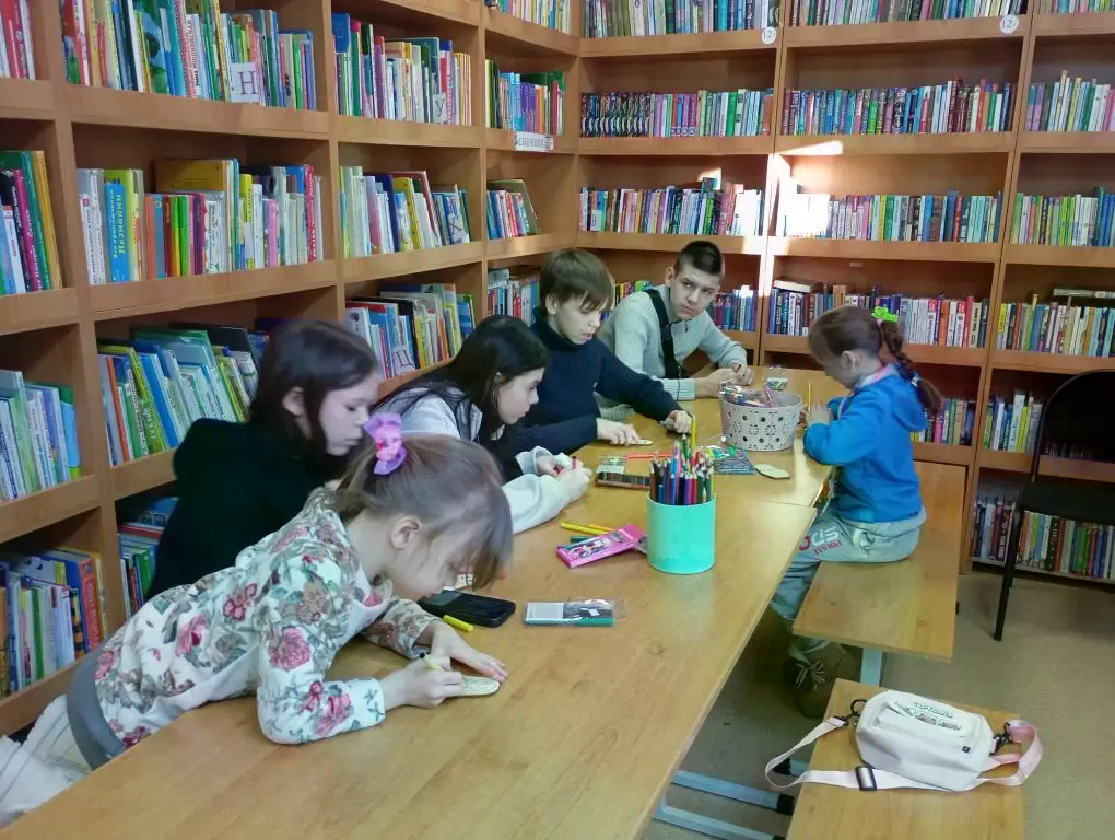 дети сидят раскрашивают за столом.png