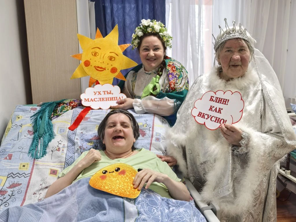 лежит женщина и стоят два ведущихс надписями.png